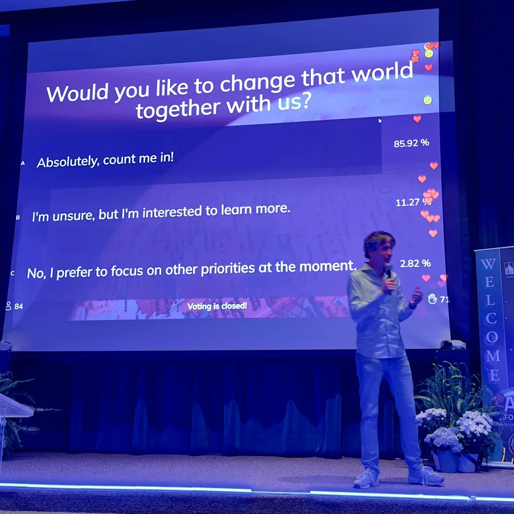 Mike Coumans op het podium met een live Sendsteps-poll op het scherm achter hem