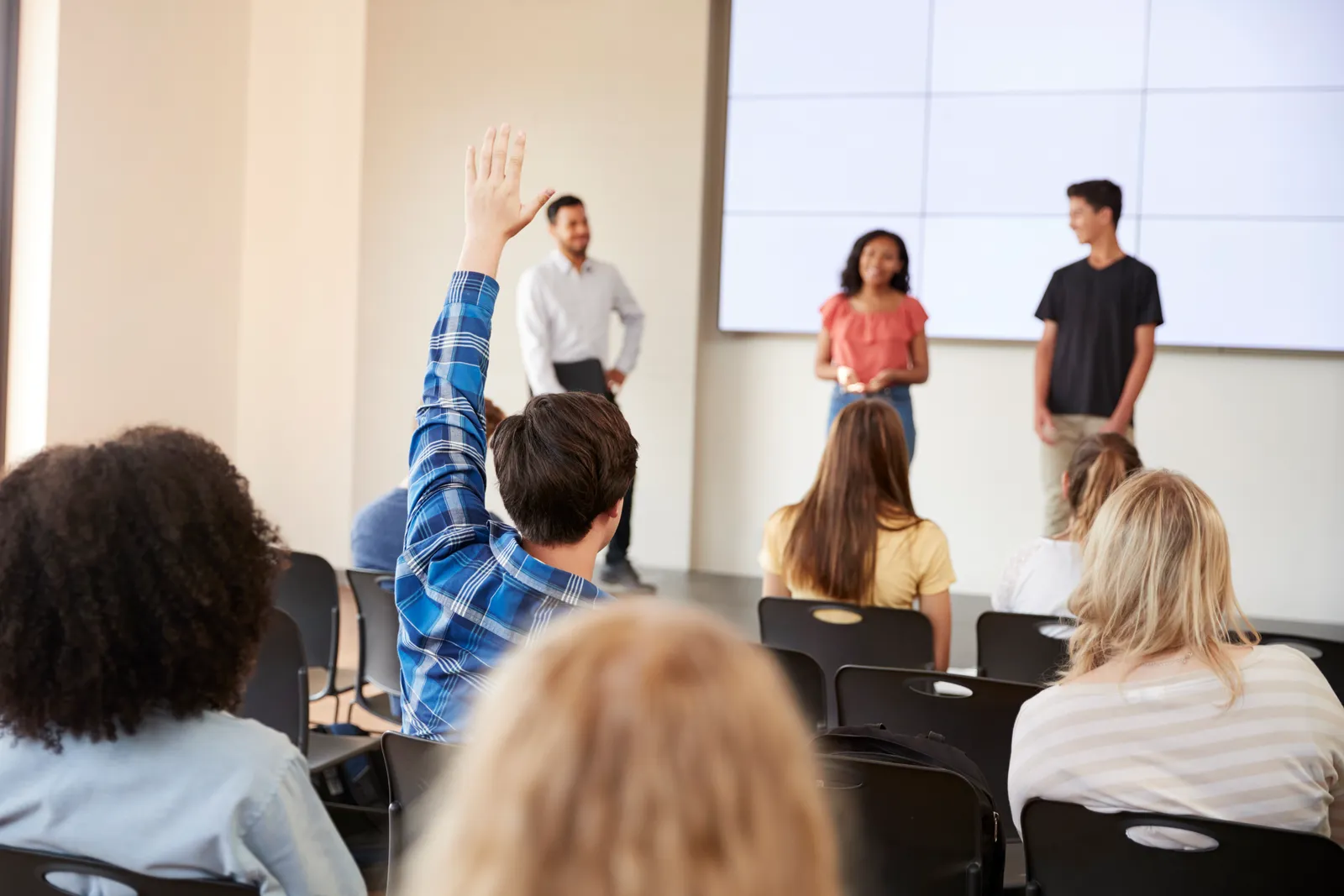 Student die een vraag stelt tijdens een presentatie in de klas