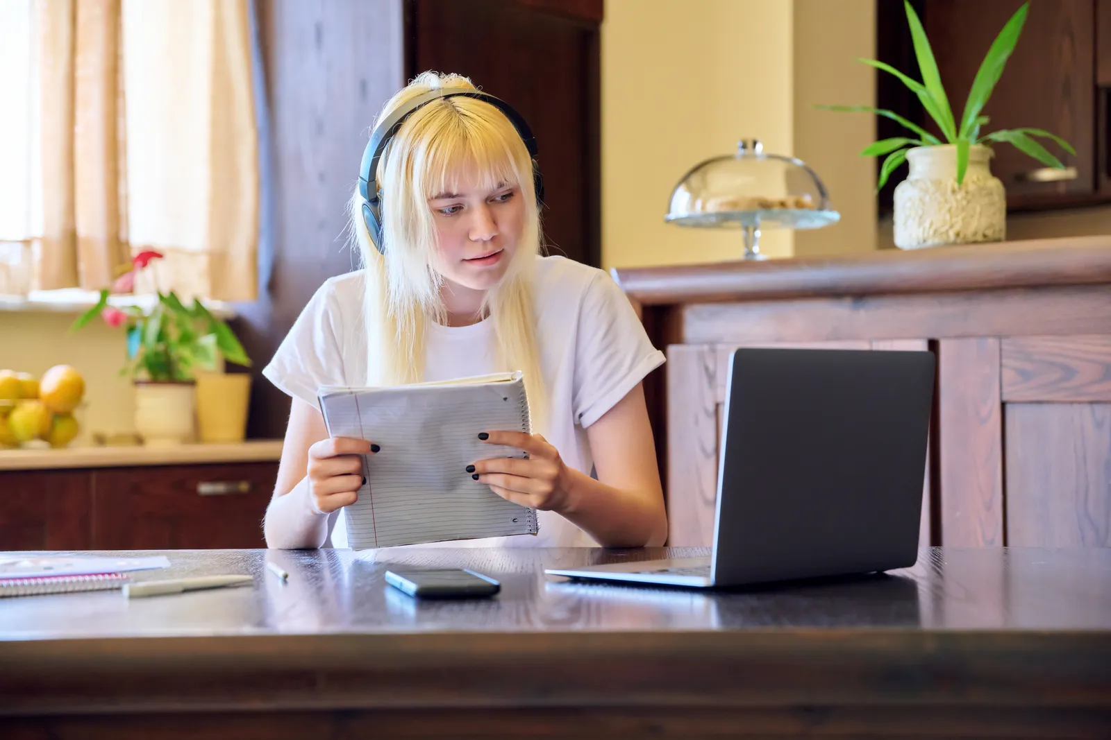 Student die lesmateriaal op een laptop bekijkt aan een keukentafel
